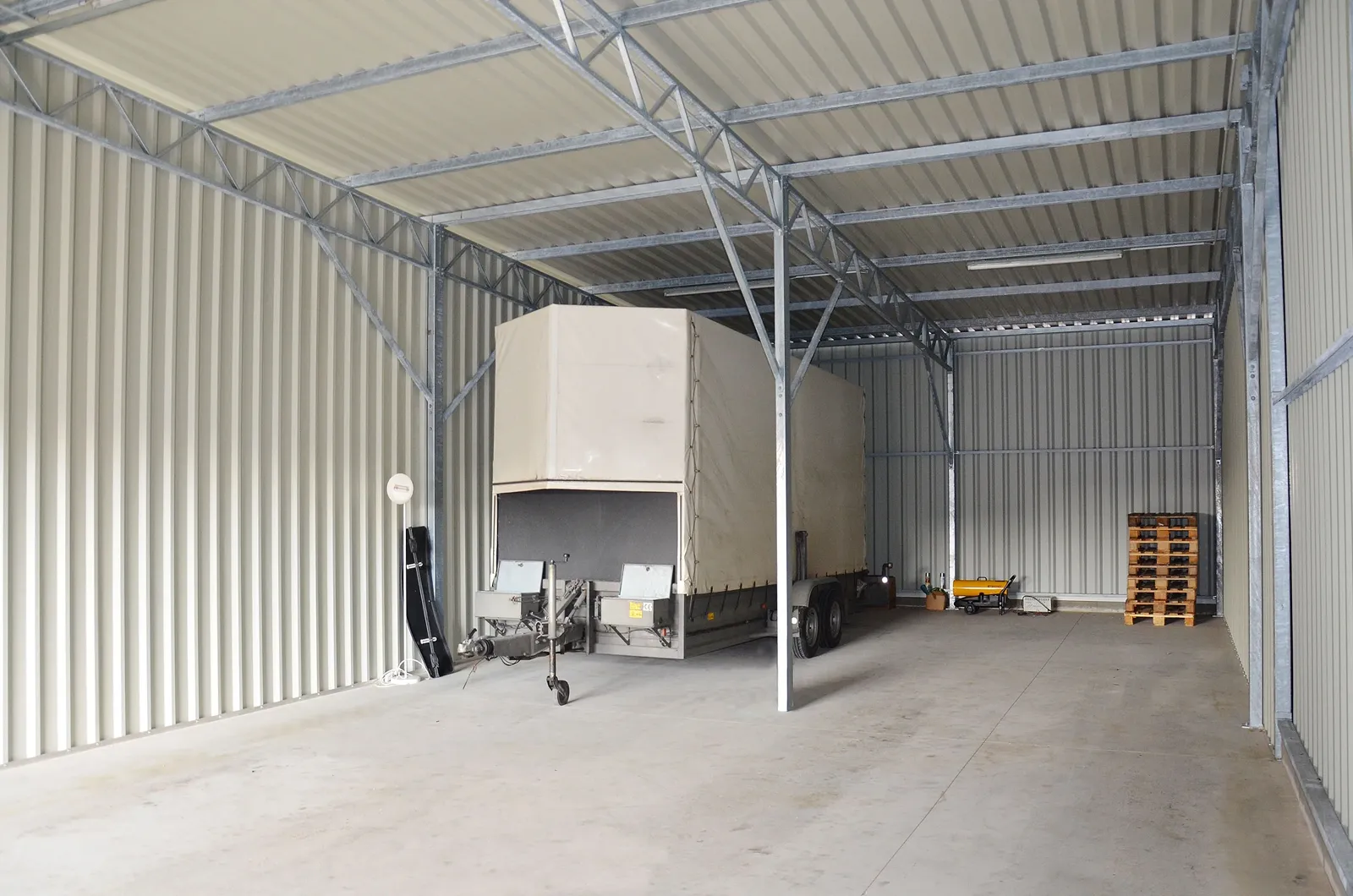 Großzügige Garage mit Anhänger und Lagerpaletten im Innenraum